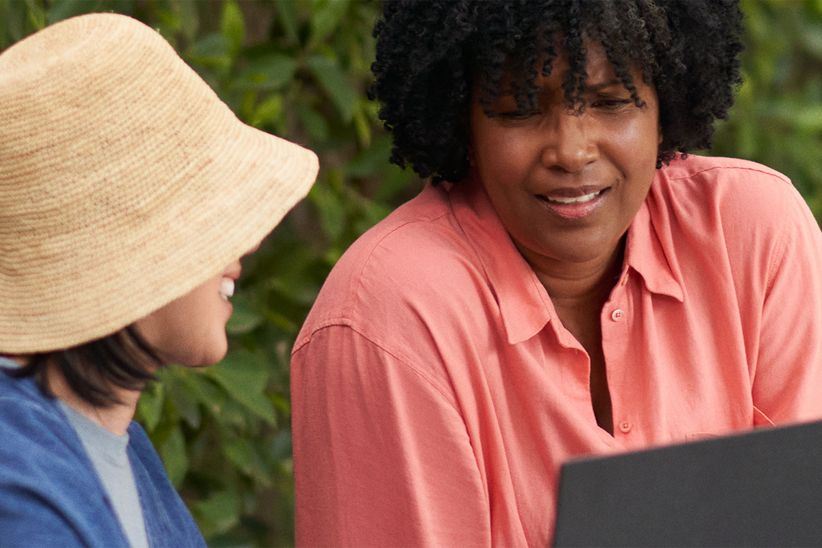 Zwei Frauen unterhalten sich, während sie einen PCSpecialist Laptop mit Windows 11 benutzen