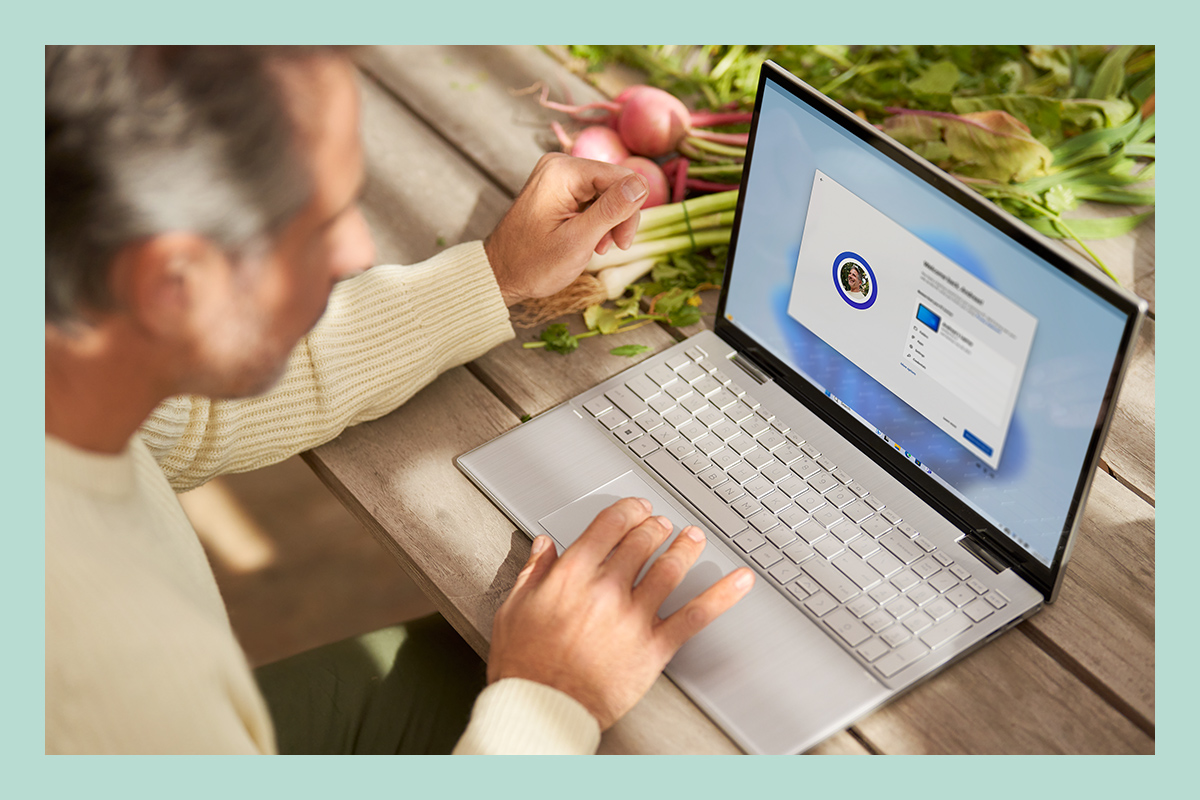 Ein Mann benutzt einen Laptop und richtet bestehende Dateien, Anwendungen und Standardkonfigurationen über Windows 11 ein.