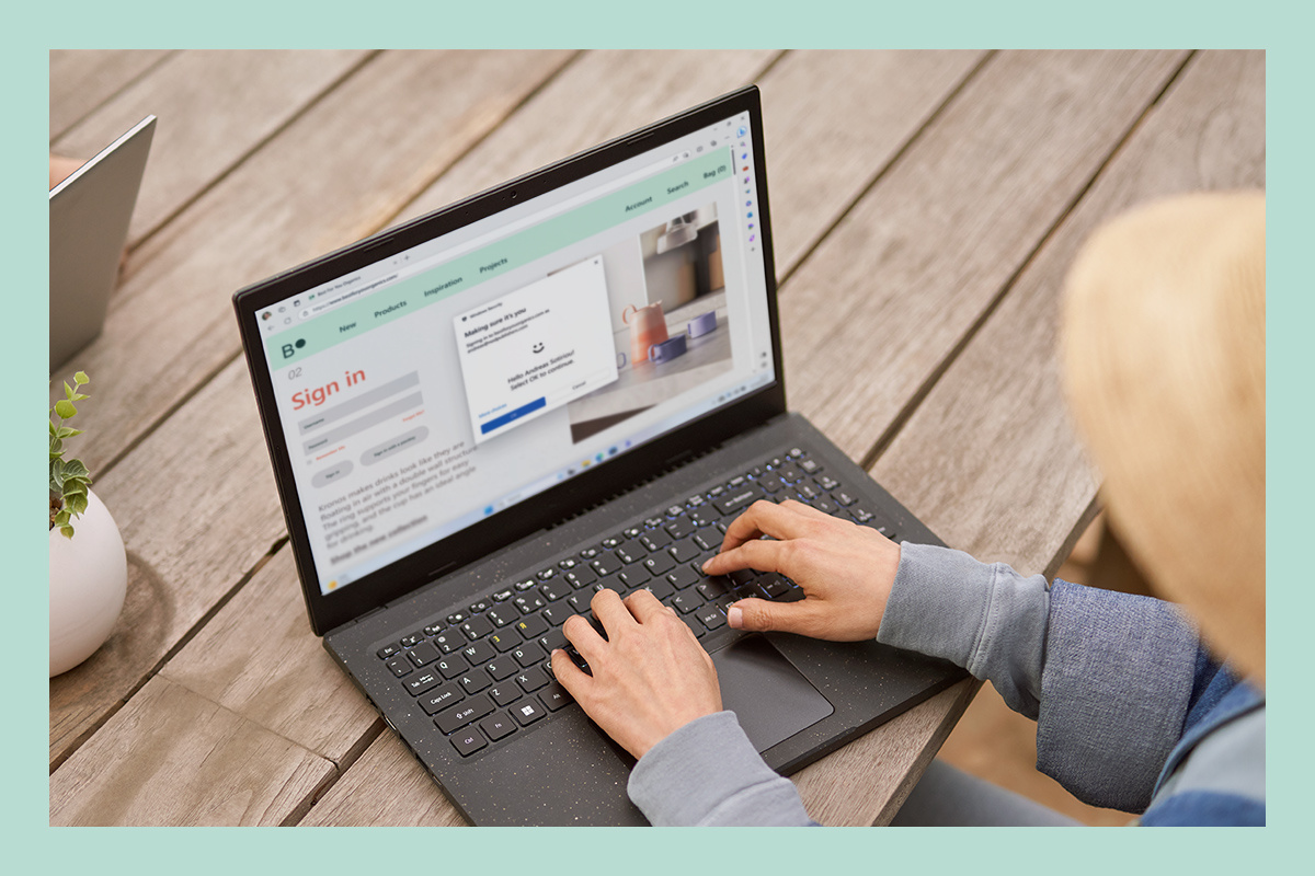 Eine Frau verwendet einen Laptop und nutzt die in Windows 11 integrierten Sicherheitsfunktionen.